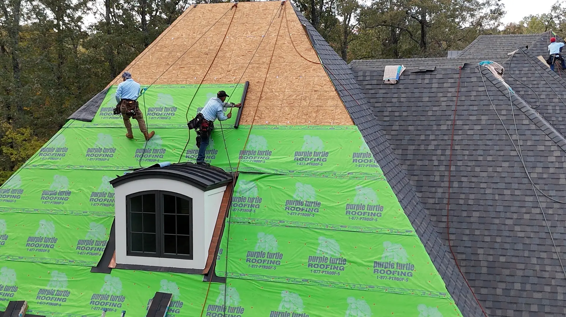 Purple Turtle Roofing crew installing branded underlayment on a steep roof